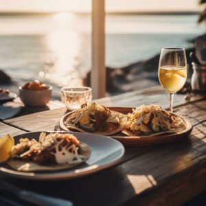 Tacos sobre una mesa, una copa de vino y el mar de fondo